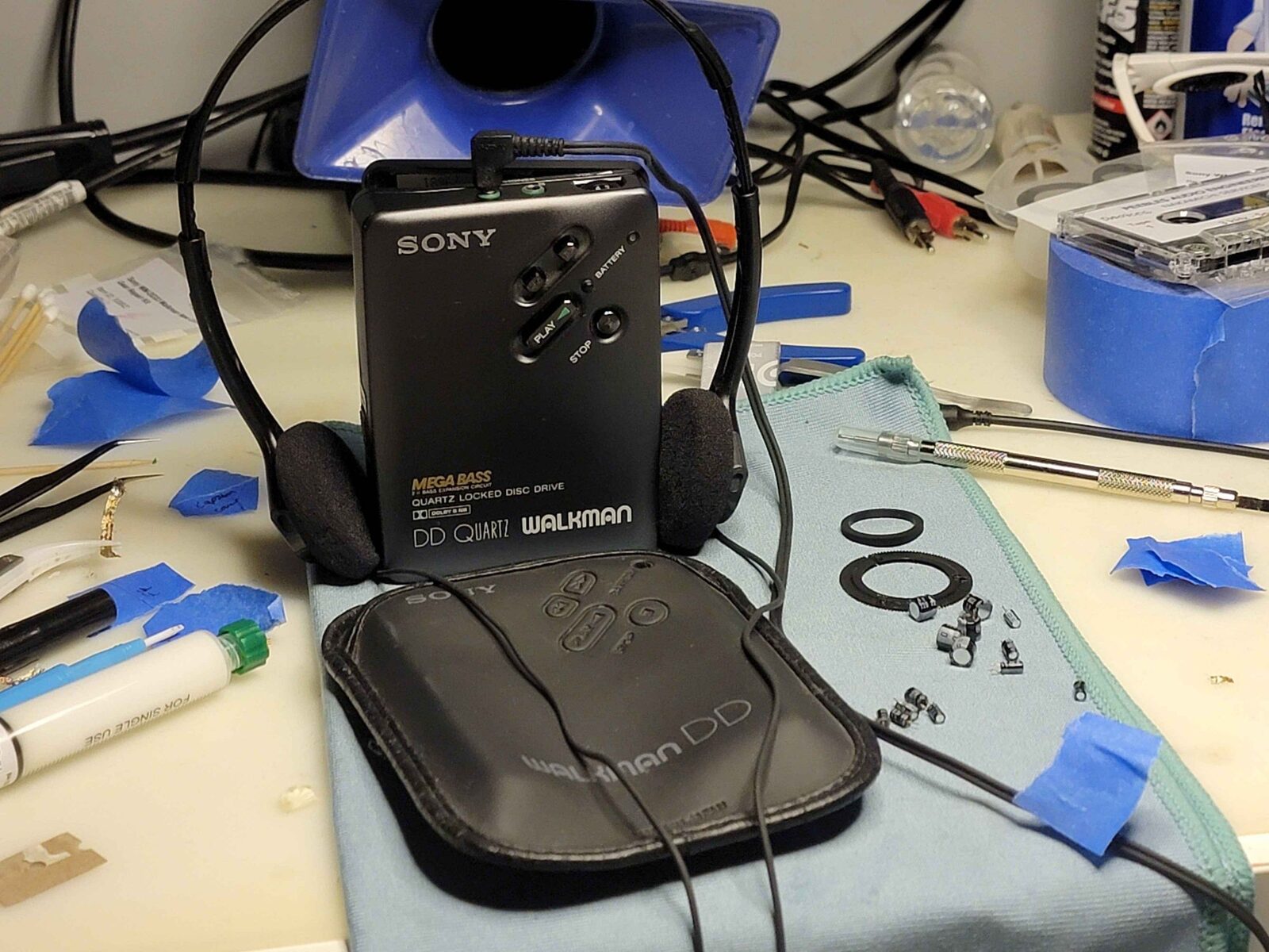 A Sony DD Quartz Walkman on the bench mid-service, with tools and replacement capacitors